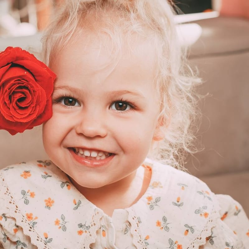 Anya radiante, acercándose una rosa roja a la cara