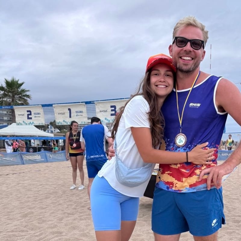 Stas y Masha abrazados en la playa tras un partido de vóley, con una medalla al cuello