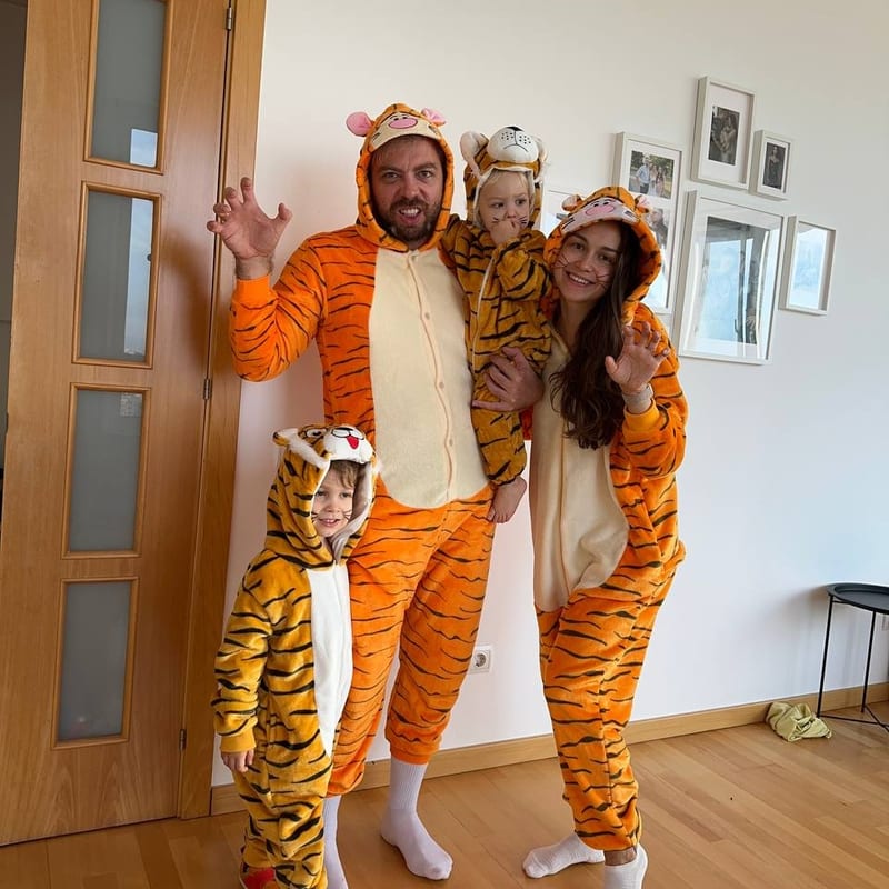 Toda la familia en casa con pijamas de tigre a juego, saludando